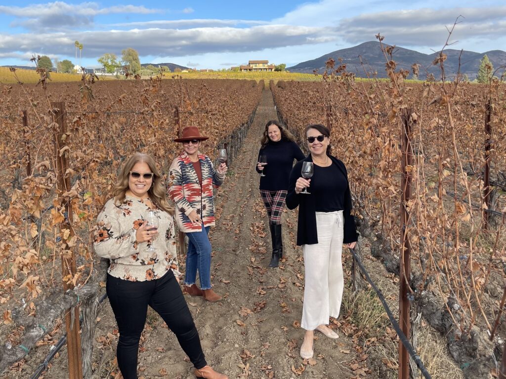 4 women in a vineyard drinking wine